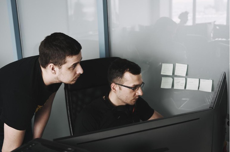 Two colleagues utilizing automation for professional services while working on computers.